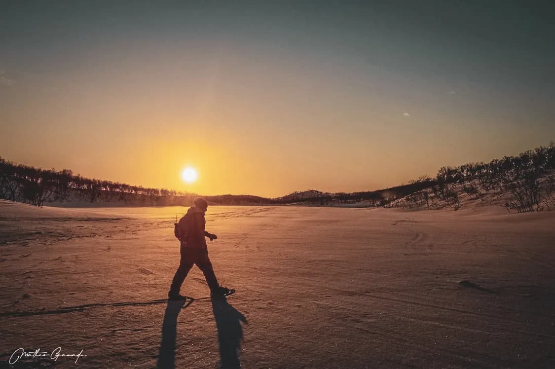 A silhouette walking through the snow, illuminated by the setting sun in Norwegian Lapland.