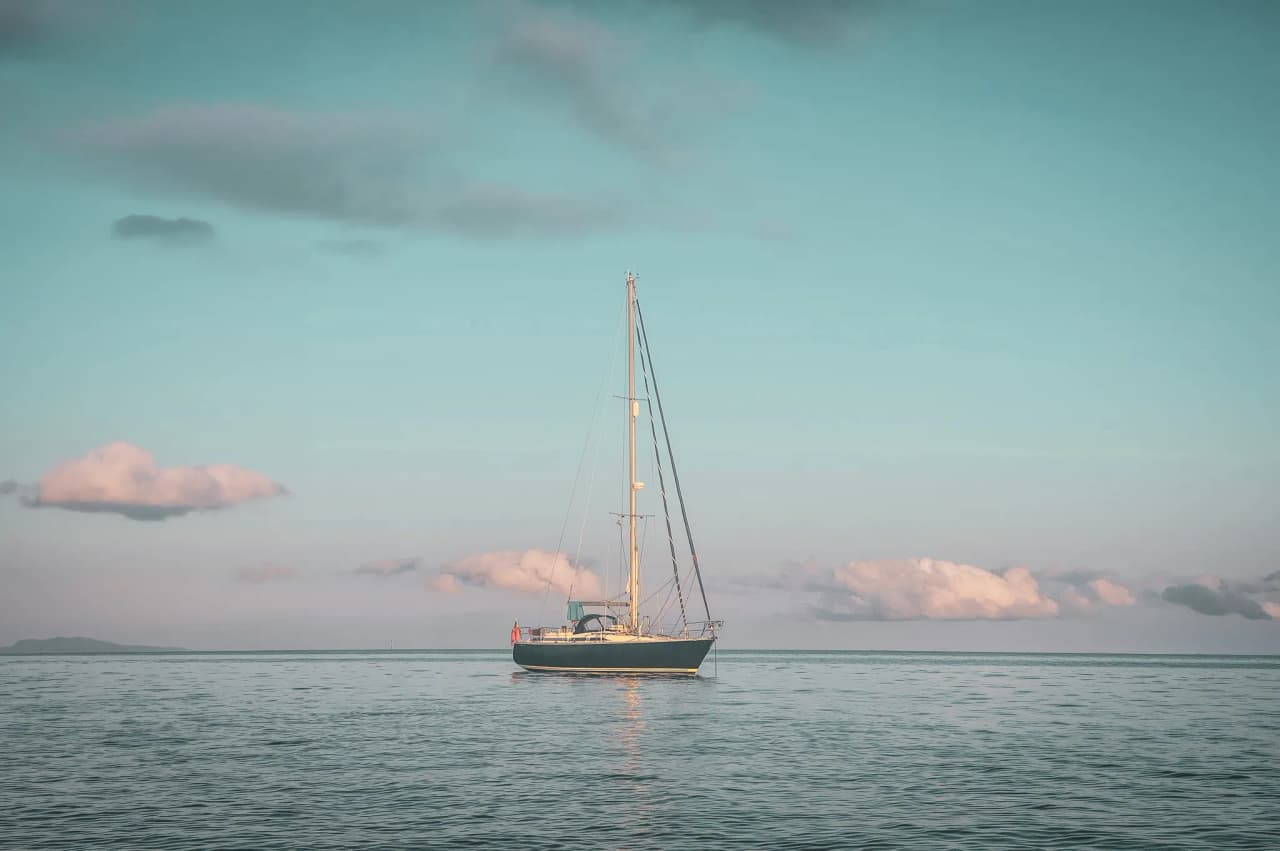 Een rustig schip aan de horizon, onder een pastelkleurige hemel, dat je uitnodigt om te ontsnappen naar Bretagne.