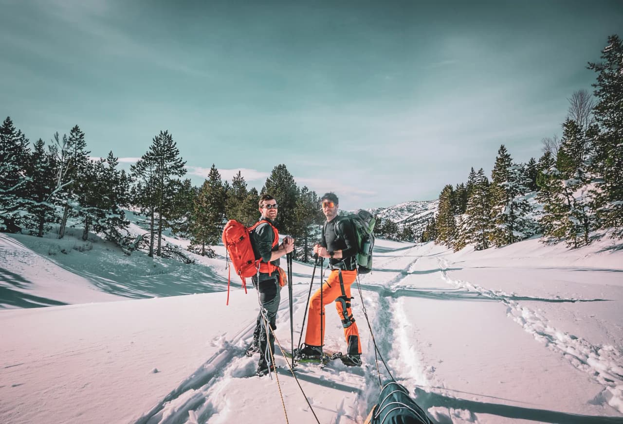Deux randonneurs souriants, équipés de raquettes, traversent un paysage enneigé du Vercors.