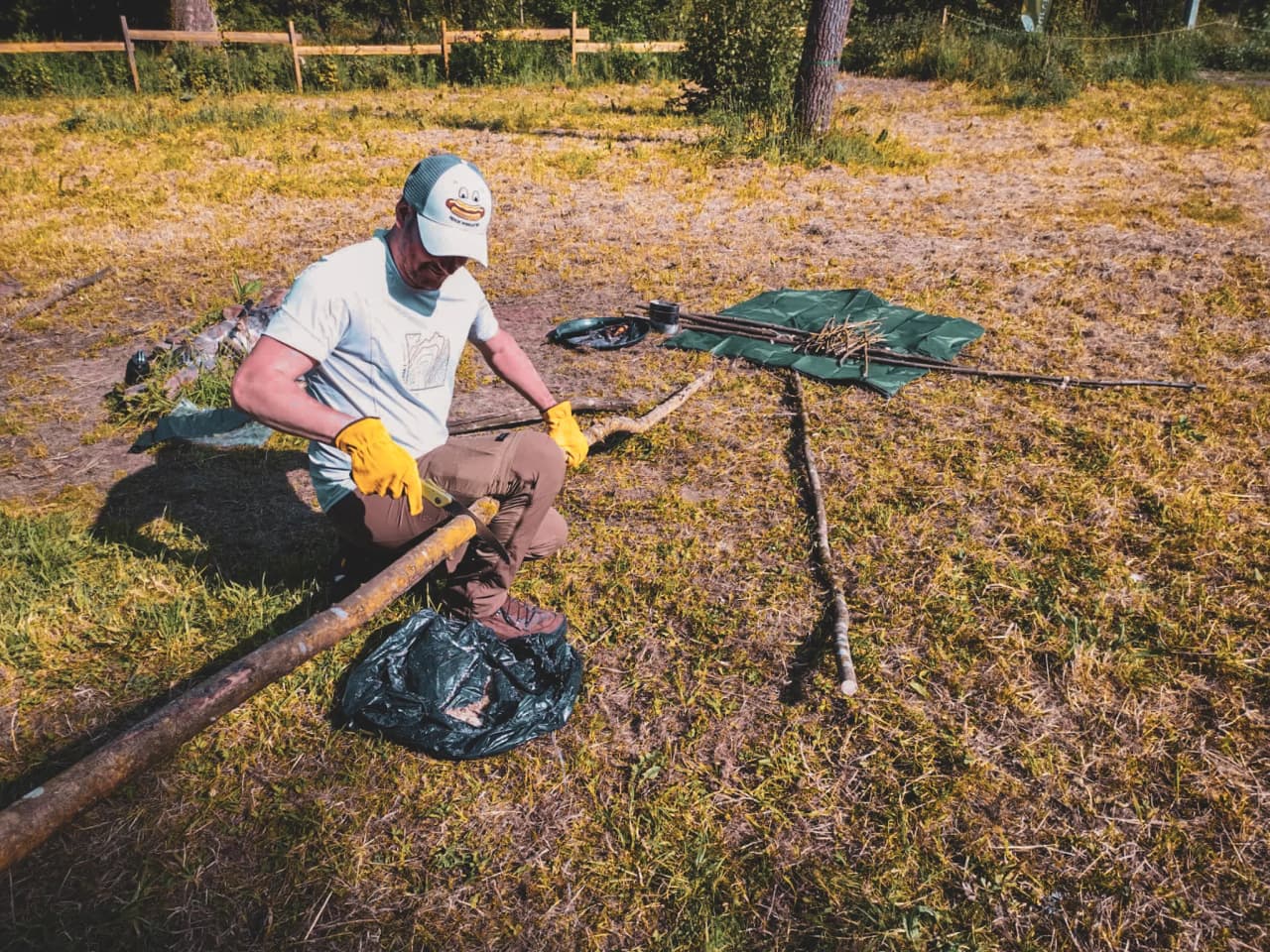 Un participant en stage de survie façonne une branche en pleine nature en Ardenne belge.