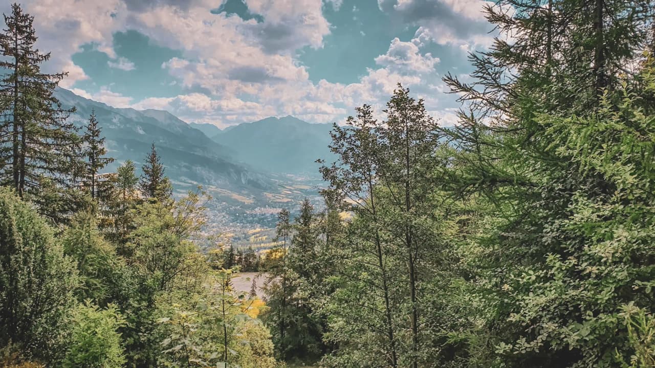 Paysage alpin verdoyant sous un ciel nuageux, invitant à l'aventure et à la découverte.
