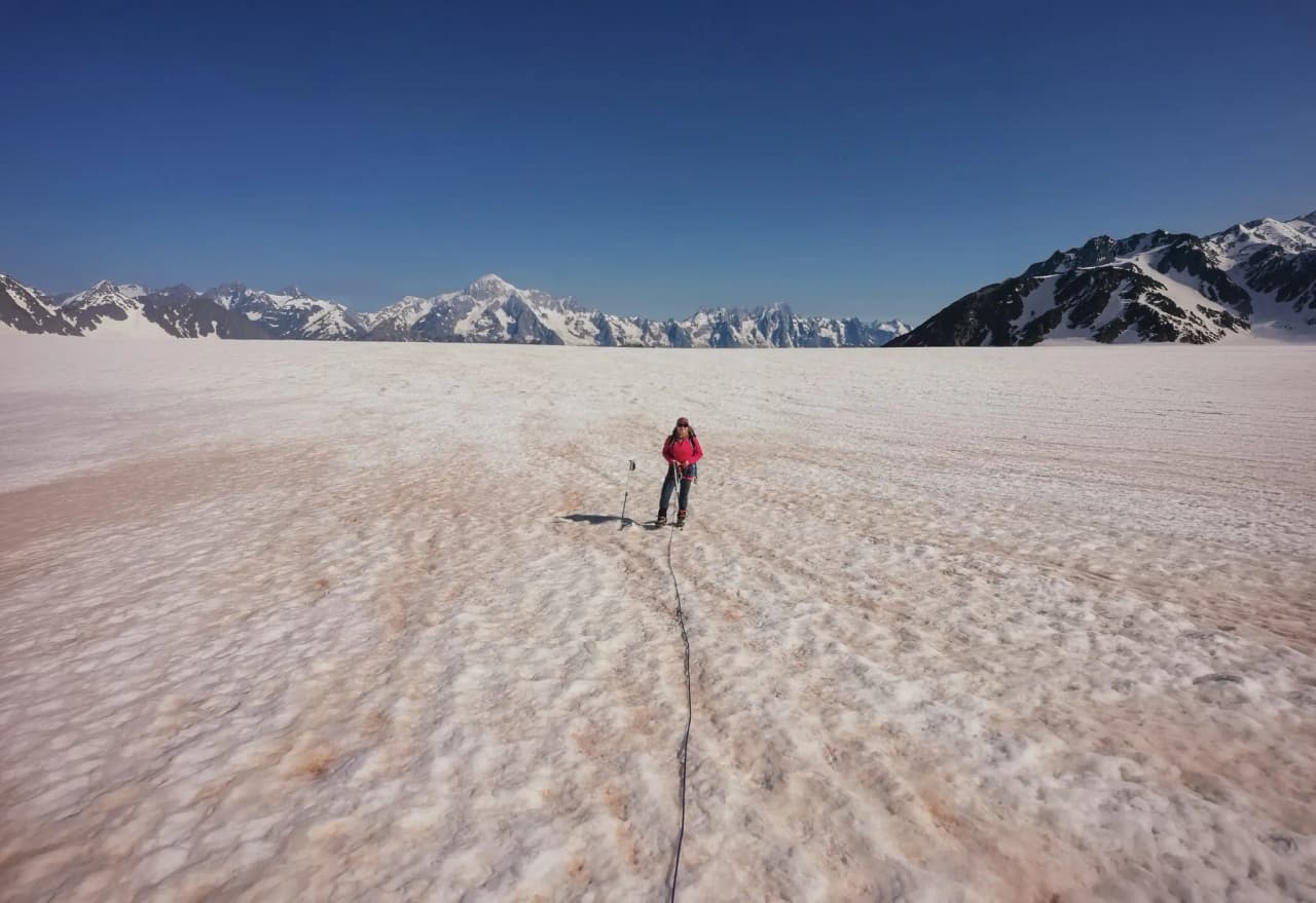 Glacier du Ruitor, un aventurier sur la neige sous un ciel azur, entouré des majestueuses Alpes.