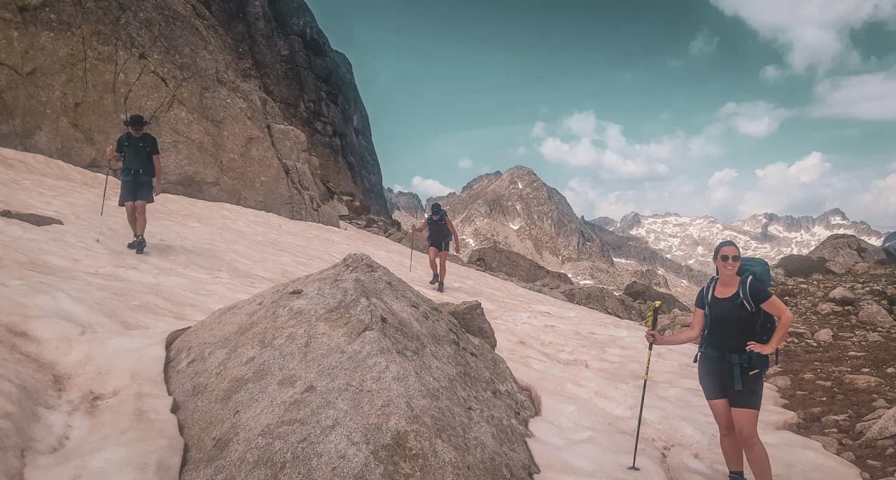 A trip to the mountains: adventurers crossing névés and rocks, majestic landscapes all around.