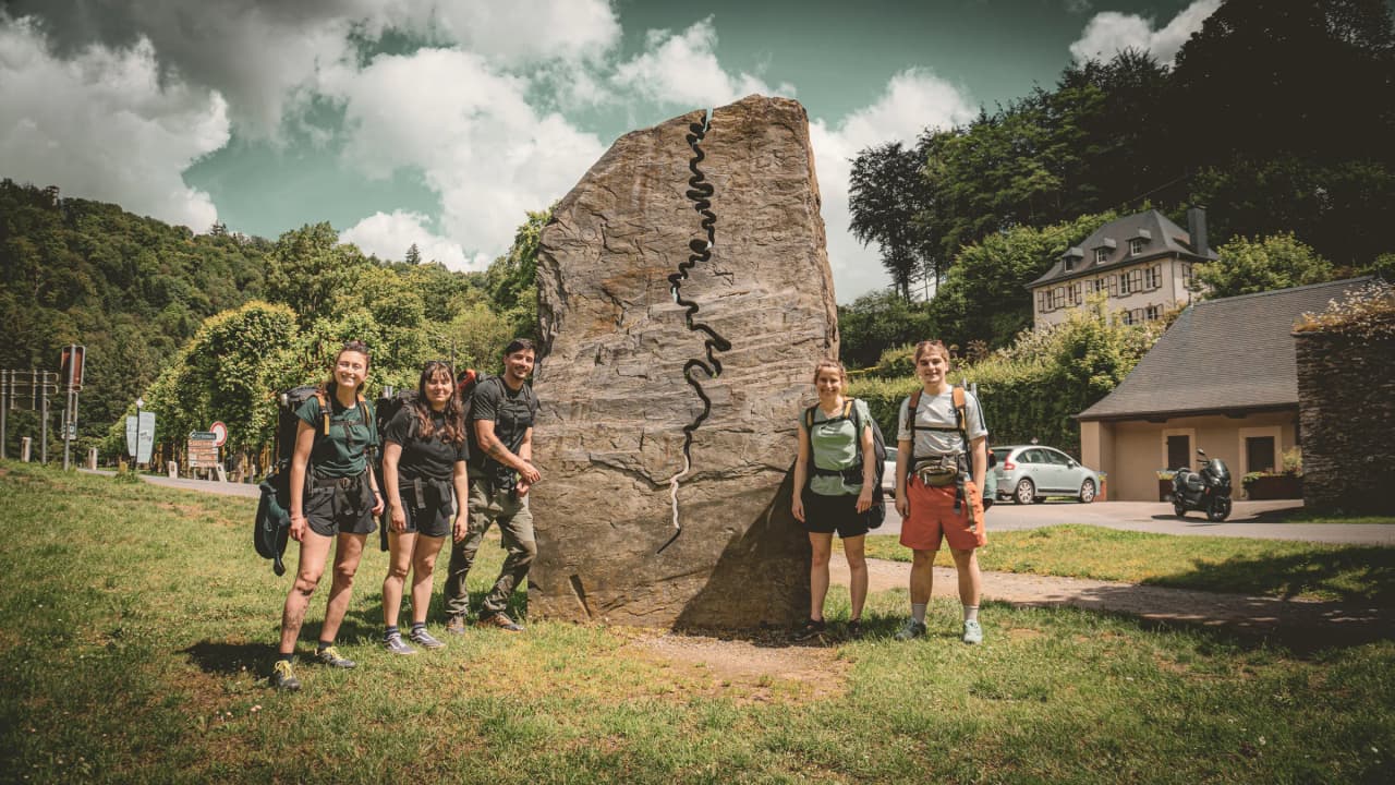 Een groep lachende avonturiers bij een uitgehouwen rots, klaar om de Semoisvallei te verkennen.