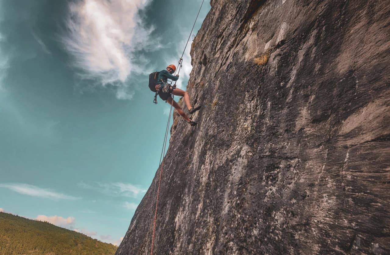 A climber climbing a rock face, using ropes and safety equipment.