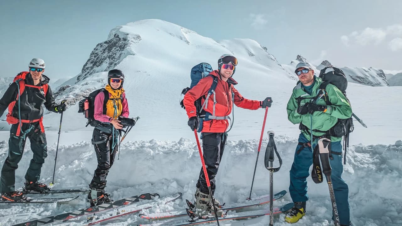 Four skiers on an expedition on the majestic glaciers of Mont Rose, under a clear sky.