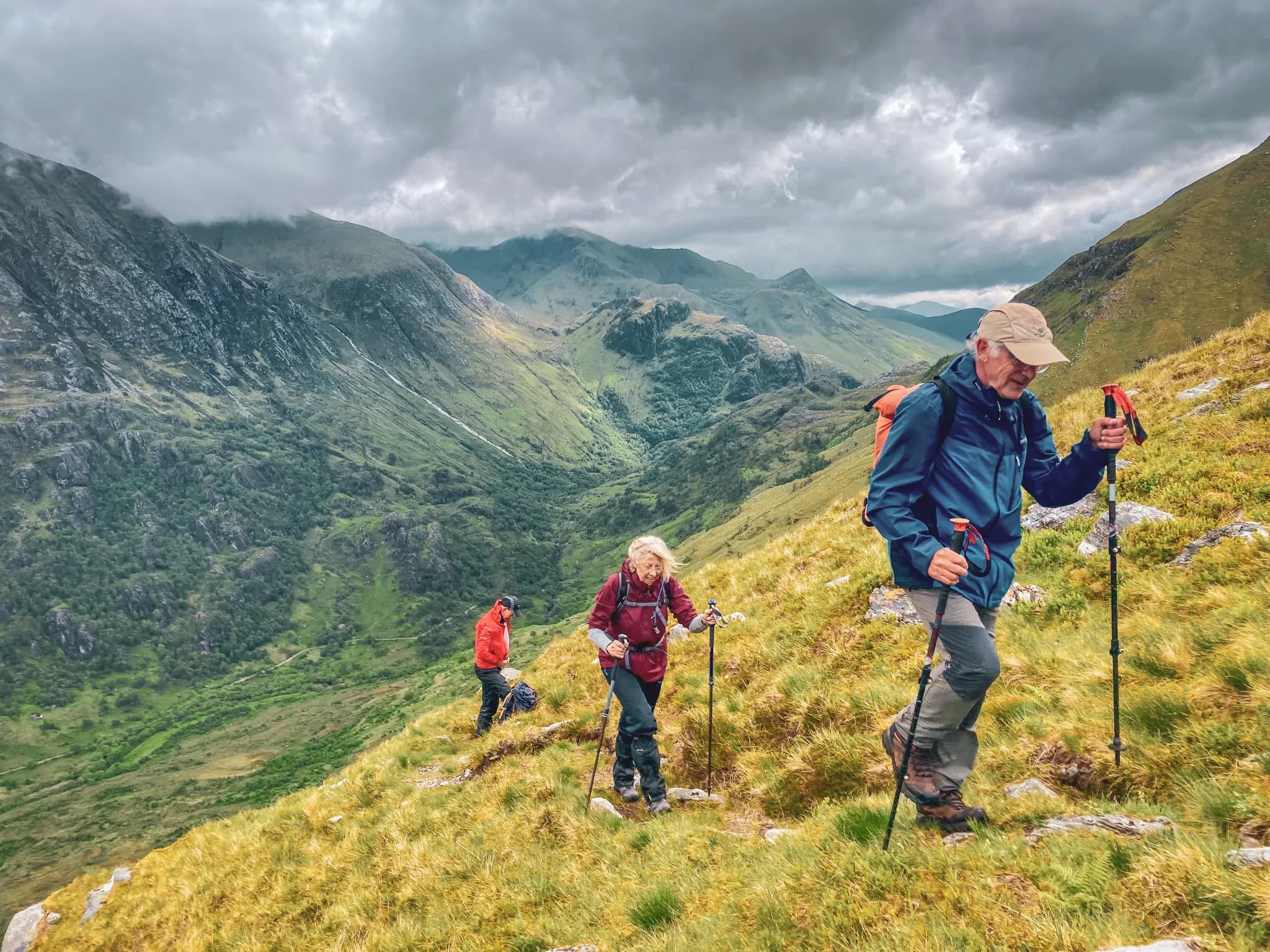 Wandelaars op de weelderig groene hellingen van de Highlands, met op de achtergrond majestueuze bergen.