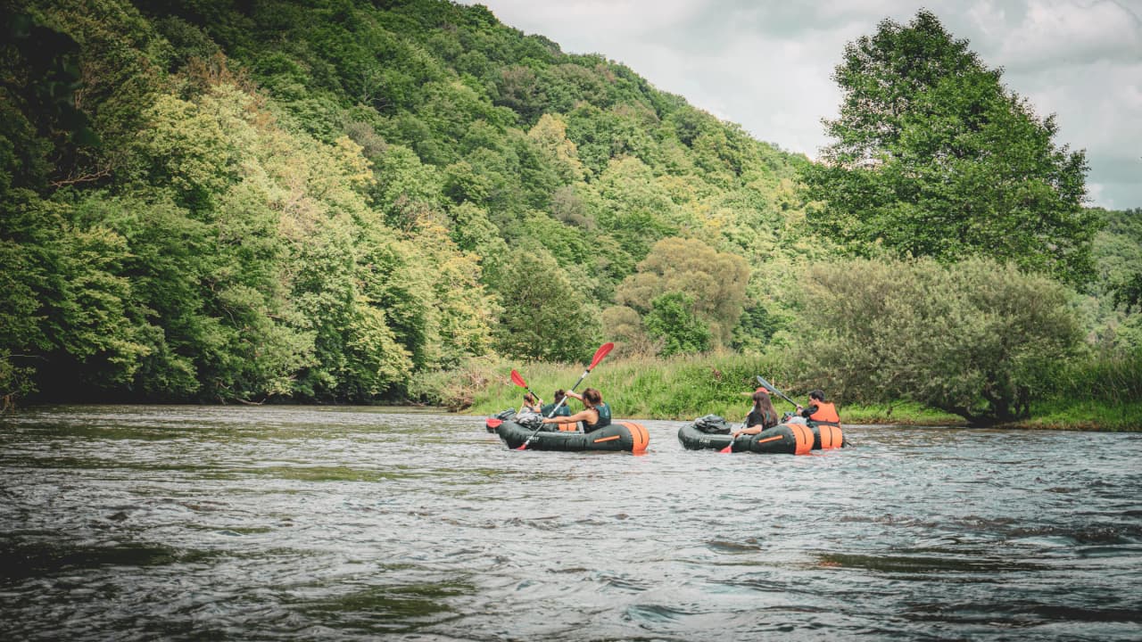 Een groep pioniers op een rivier, omgeven door weelderig groen, een uitnodiging tot avontuur.