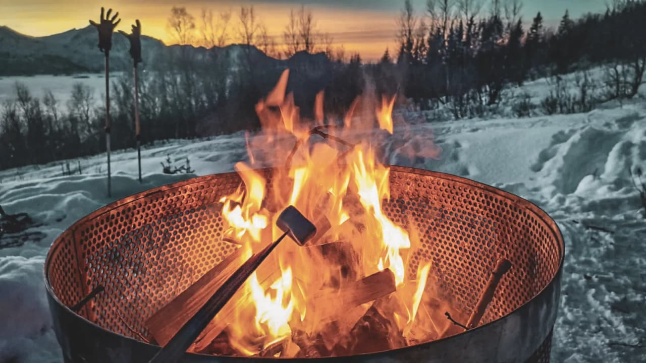A crackling fire at dusk in a snow-covered landscape, ideal for a cosy evening in Norway.