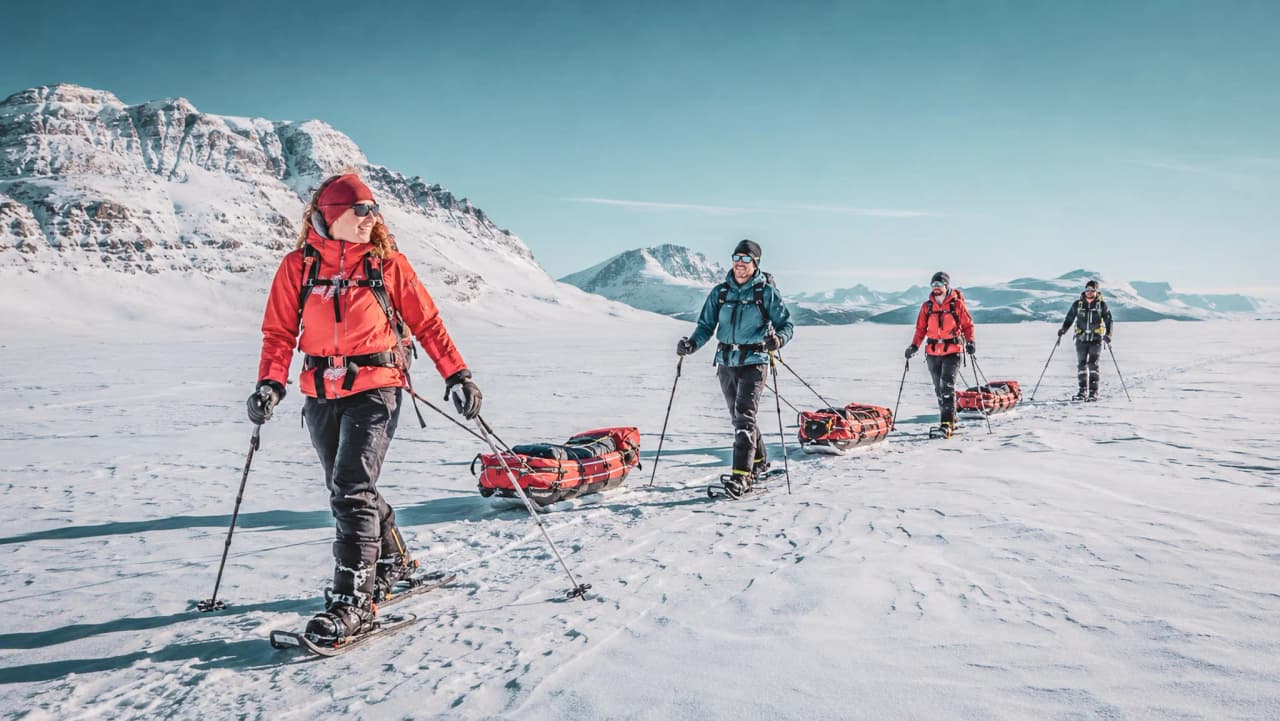 Een groep avonturiers op sneeuwschoenen in de arctische sneeuw, die de majestueuze landschappen van Lapland verkennen.