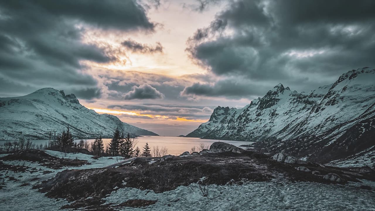Een adembenemend sneeuwlandschap in Tromsø, met majestueuze bergen en een indrukwekkende lucht.
