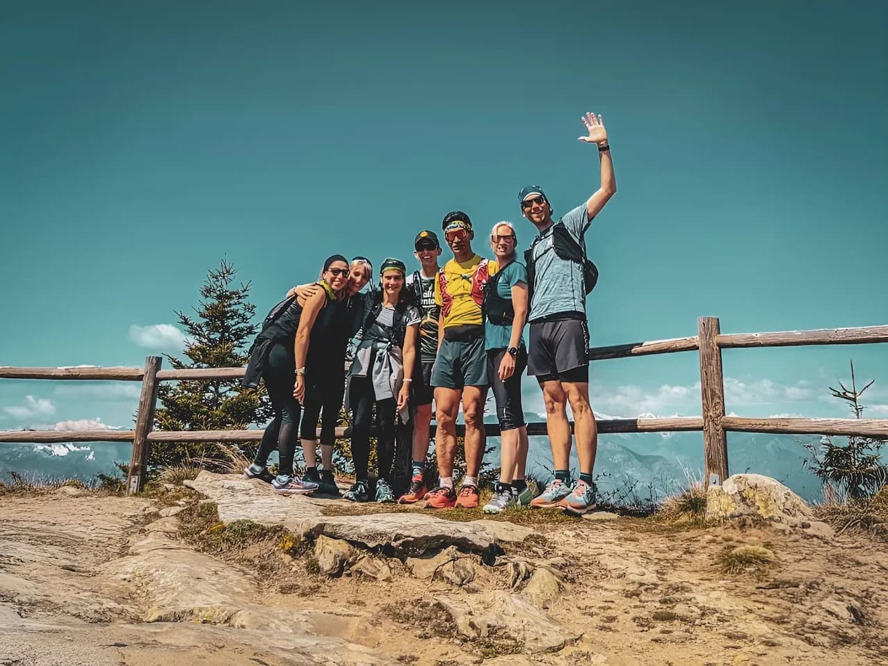 Groupe souriant en randonnée dans le parc du Mercantour, ciel bleu et paysages majestueux.