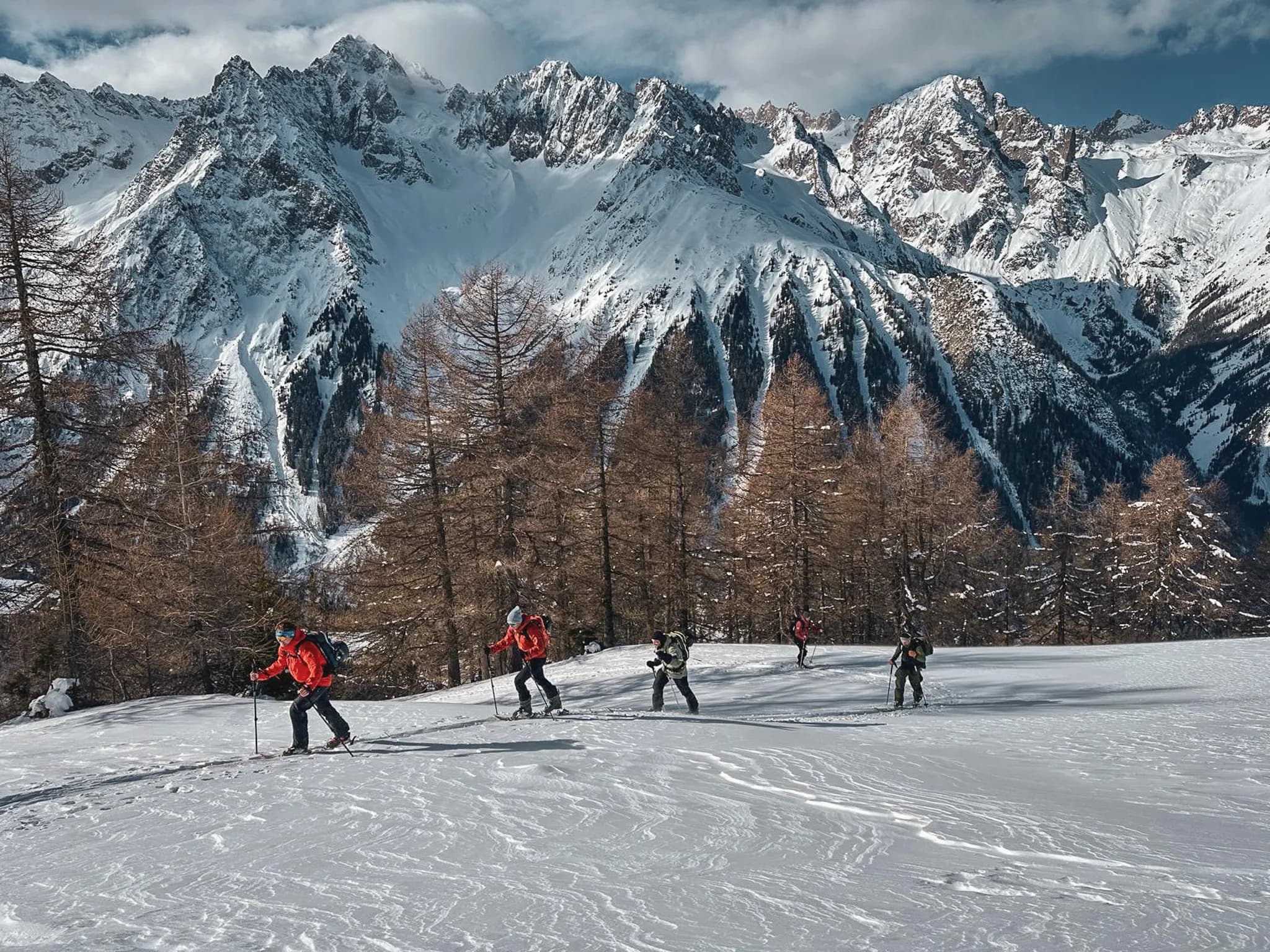 A group of skiers on an alpine tour with majestic peaks in the background.