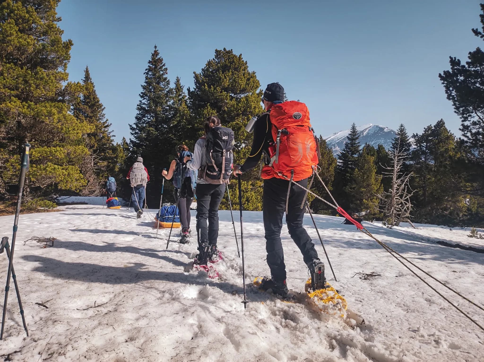 Groep avonturiers op sneeuwschoenen, met de bergen op de achtergrond.