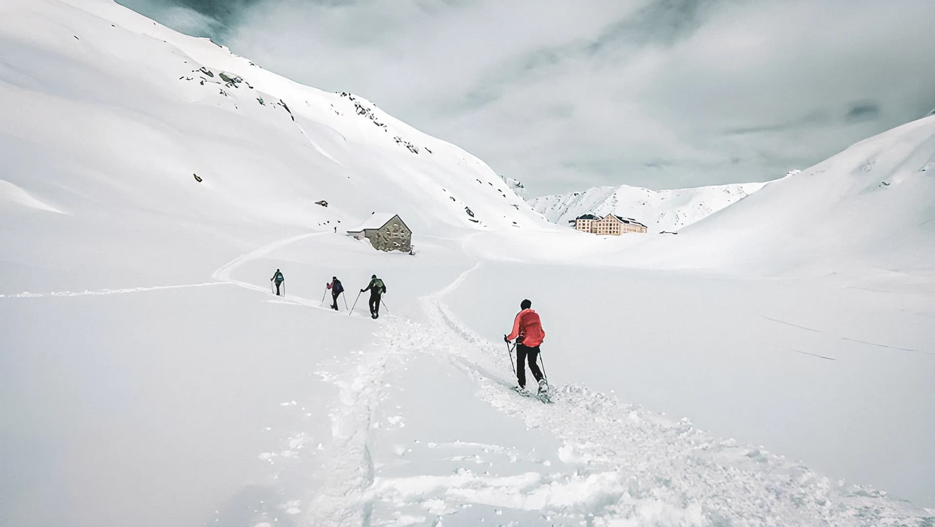 Een groep wandelaars op sneeuwschoenen doorkruist besneeuwde landschappen op weg naar het hospice.
