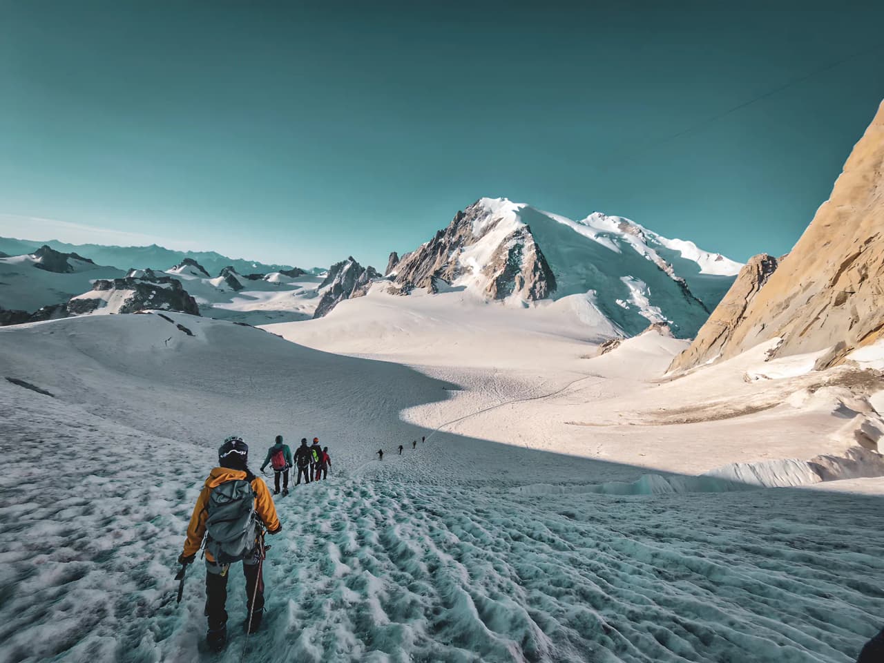 A group of hikers on a glacier, with the majestic Mont Blanc in the background.