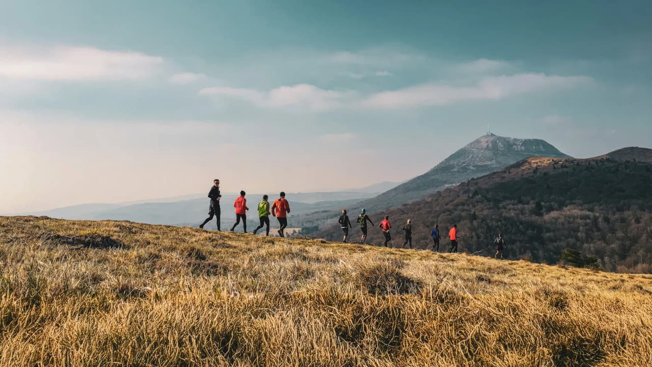 Runners in the great outdoors, exploring the Auvergne volcanoes under clear skies.