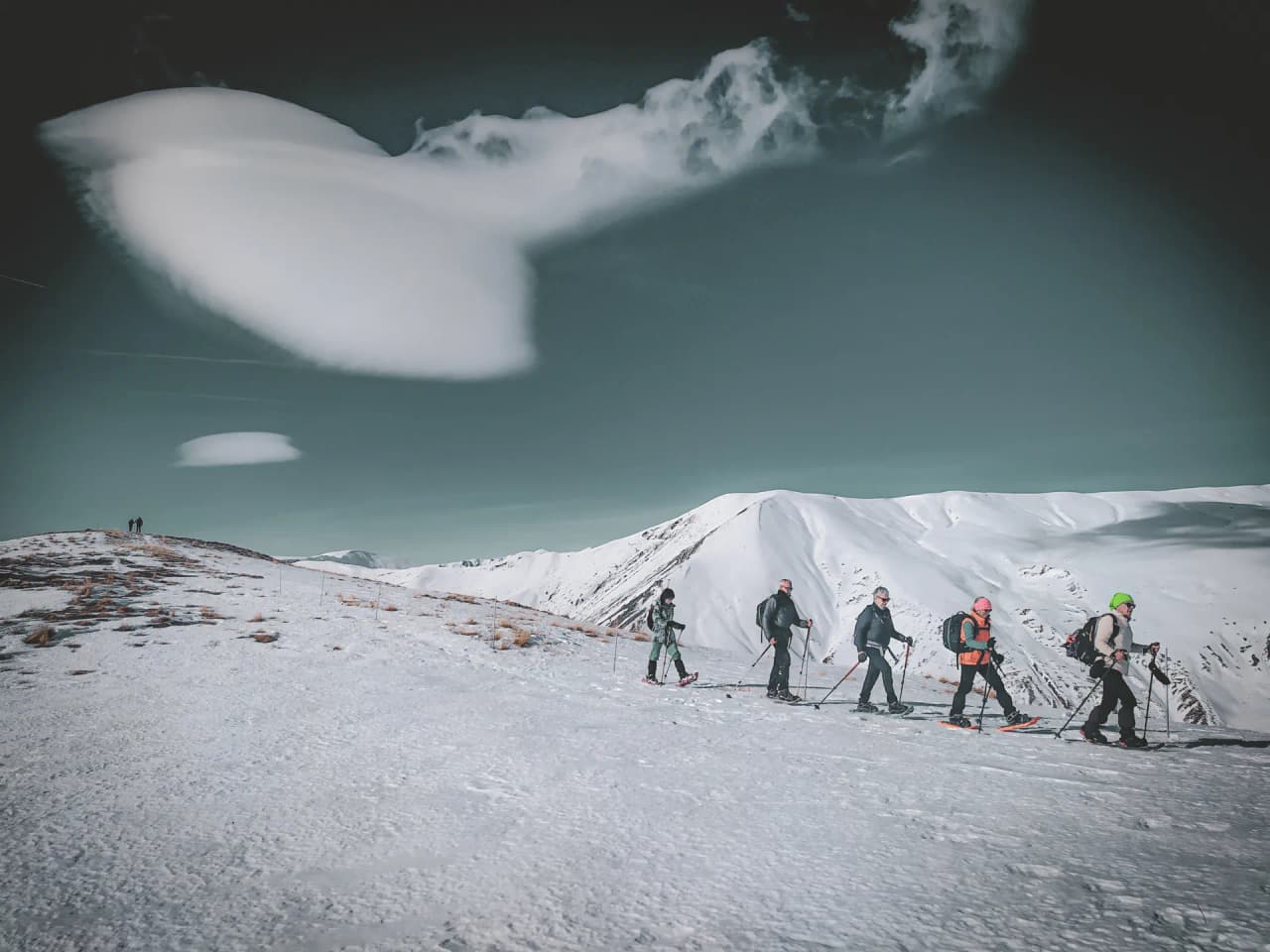 Een groep ontdekkingsreizigers op sneeuwschoenen baant zich een weg door een magisch, besneeuwd alpenlandschap.