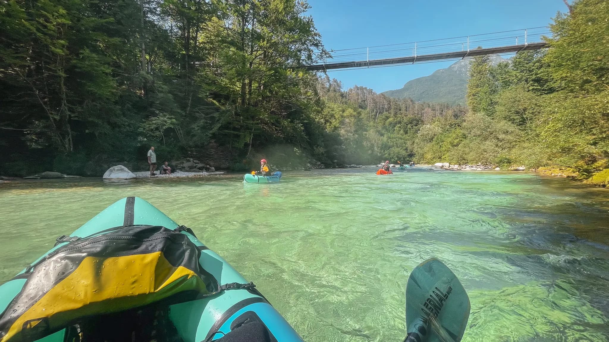 Packraft sur une rivière cristalline en Slovénie, entouré de verdure et de montagnes majestueuses.