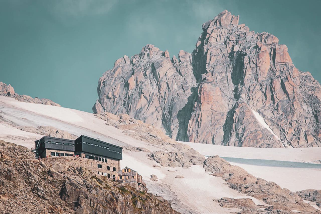 Spectacular views of an alpine mountain hut, surrounded by rocky peaks and pristine glaciers.