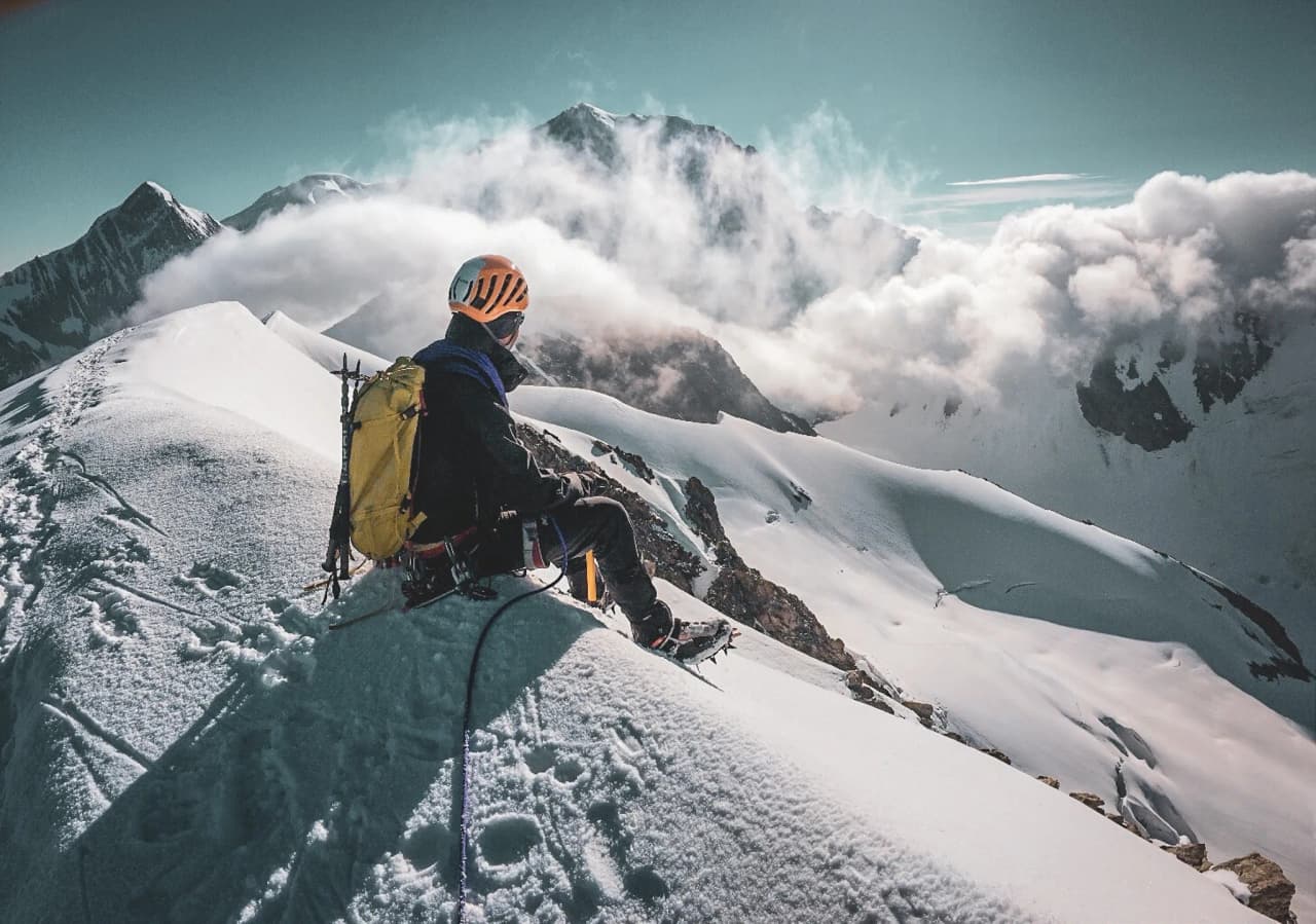 Bergbeklimmer kijkt uit over een adembenemend panorama van de Dômes de Miage en de Mont Blanc.