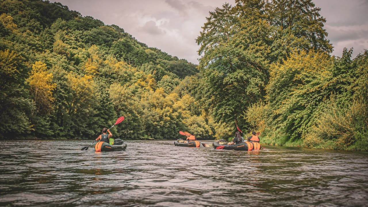 Adventurers paddling happily in packraft in the heart of lush nature.