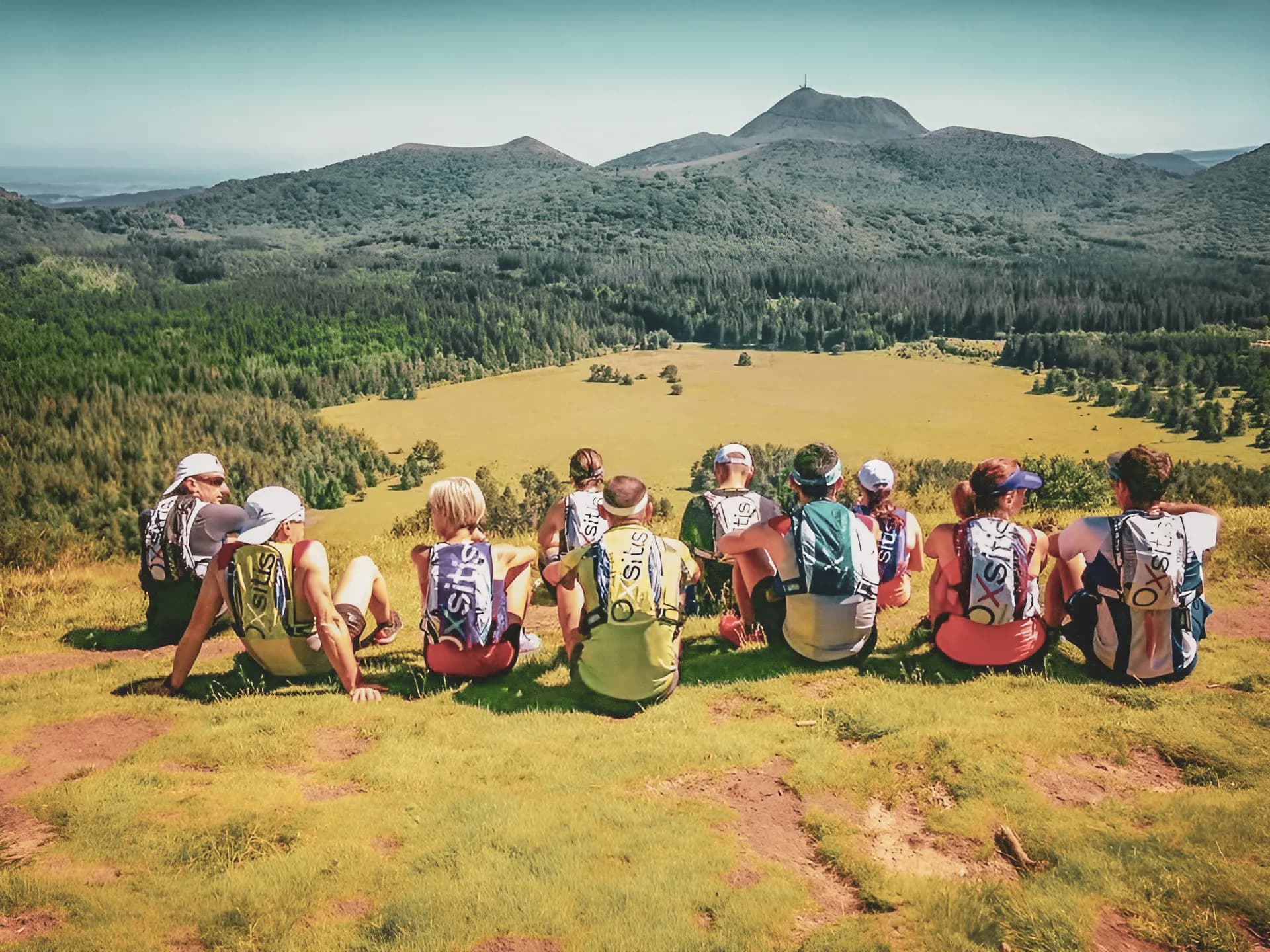 Een groep wandelaars bewondert de vulkanen van de Auvergne onder een zonnige hemel.