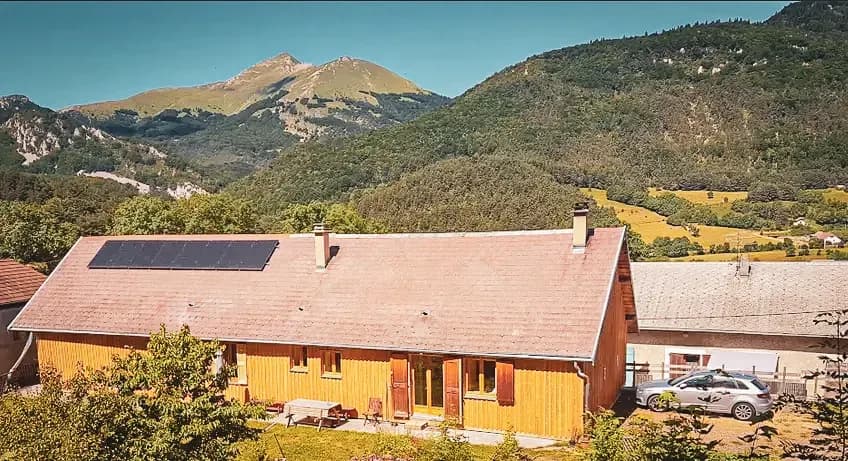 Houten chalet omringd door weelderig groene bergen, perfect om het Alpenlandschap te verkennen.
