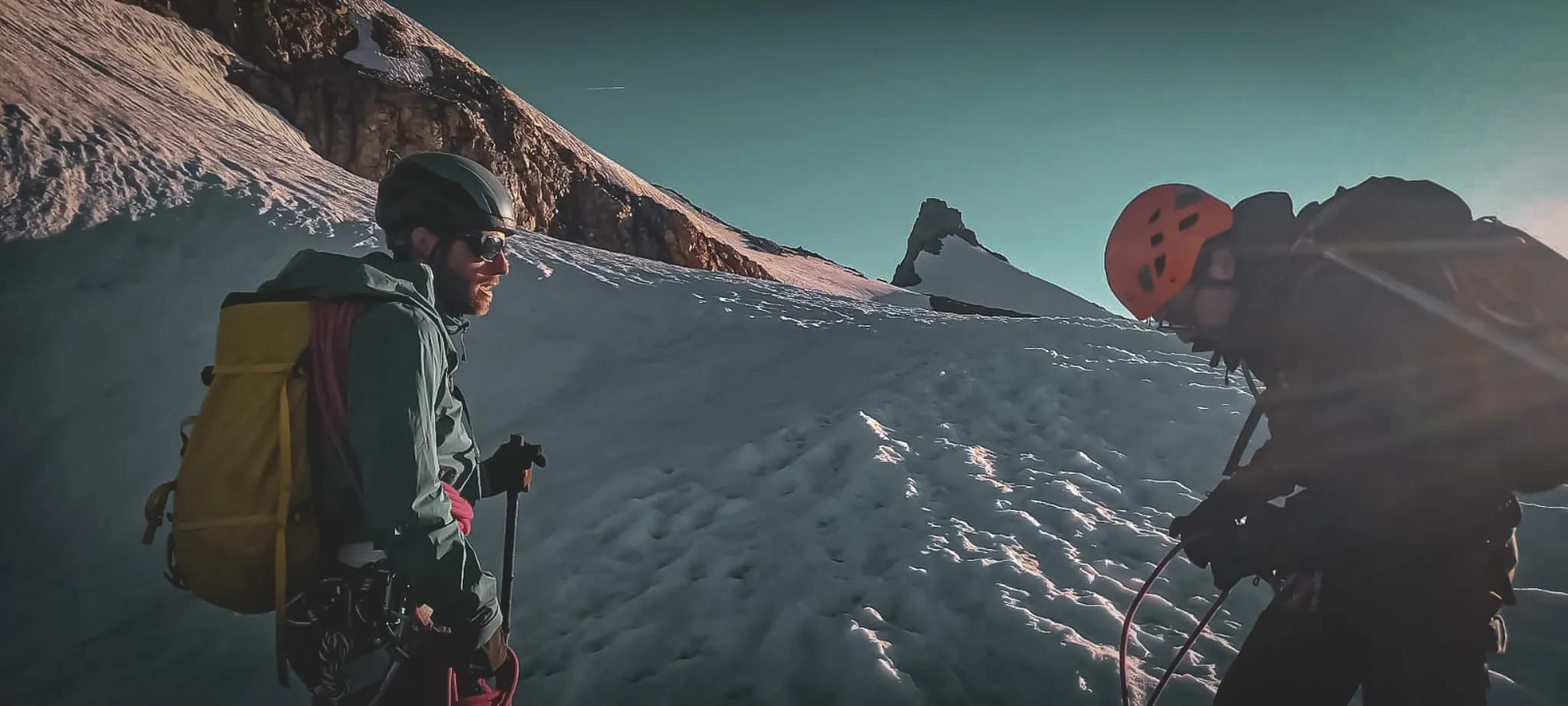 Deux alpinistes en montagne, entourés de neige et de sommets majestueux, prêts pour l'aventure.