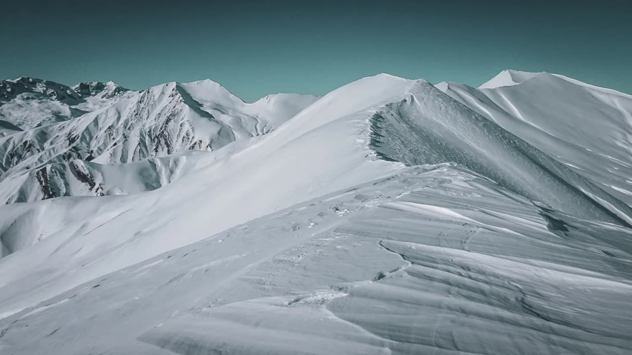 Vastes sommets enneigés sous un ciel bleu, invitation à l'aventure en ski de randonnée.