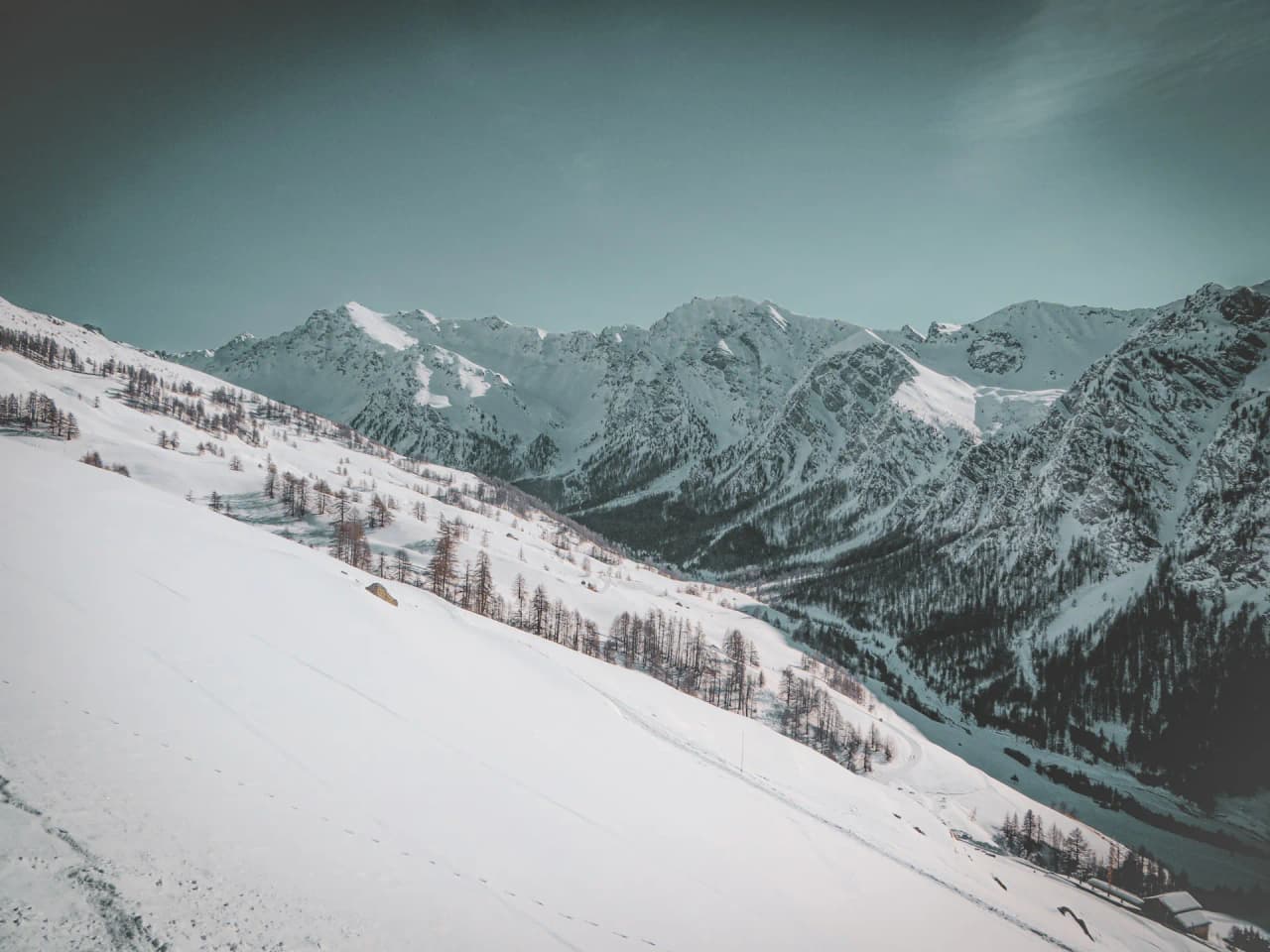 Besneeuwde Alpenlandschappen, majestueuze valleien en bergen onder een heldere hemel, een uitnodiging tot avontuur.