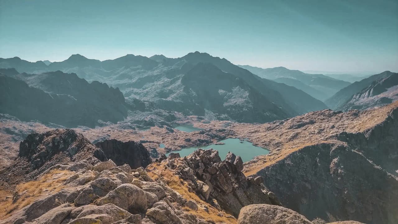 Majestic panorama of the Encantats mountains, with sparkling lakes and sun-drenched valleys.