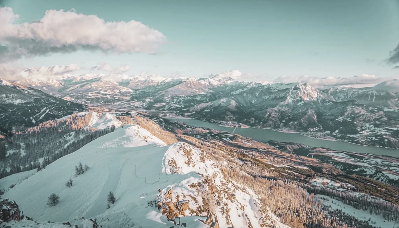 Vue à couper le souffle du lac de Serre-Ponçon enneigé, entouré de montagnes majestueuses.