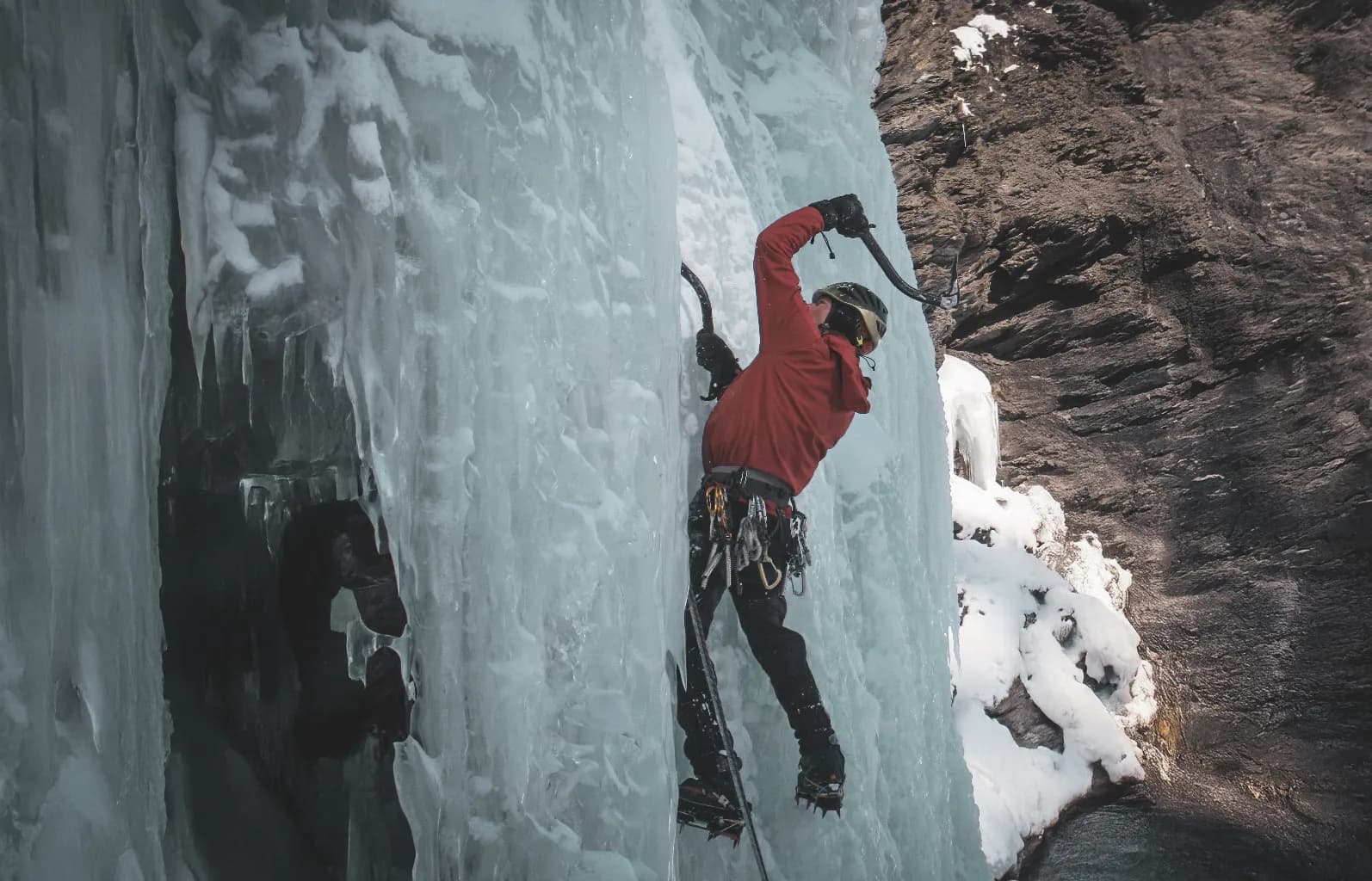 Un grimpeur s'attaque à une cascade de glace majestueuse, entouré de paysages alpins enchanteurs.