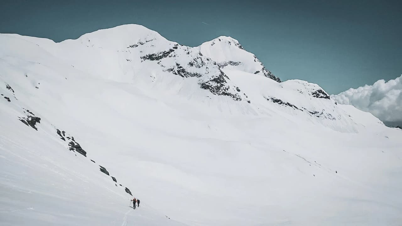 Two hikers on the immaculate glaciers of the Vanoise, under a soothing blue sky.