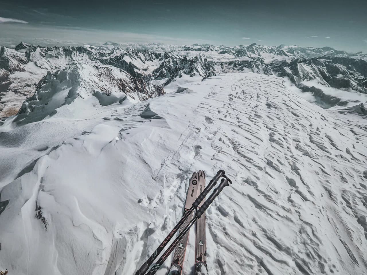 Vue splendide depuis le sommet du Mont Blanc, skis prêts à descendre sur un manteau neigeux.
