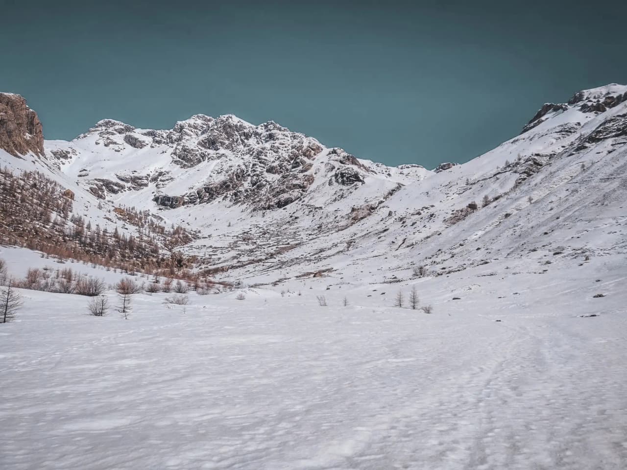Un paysage enneigé spectaculaire avec des montagnes majestueuses sous un ciel bleu.