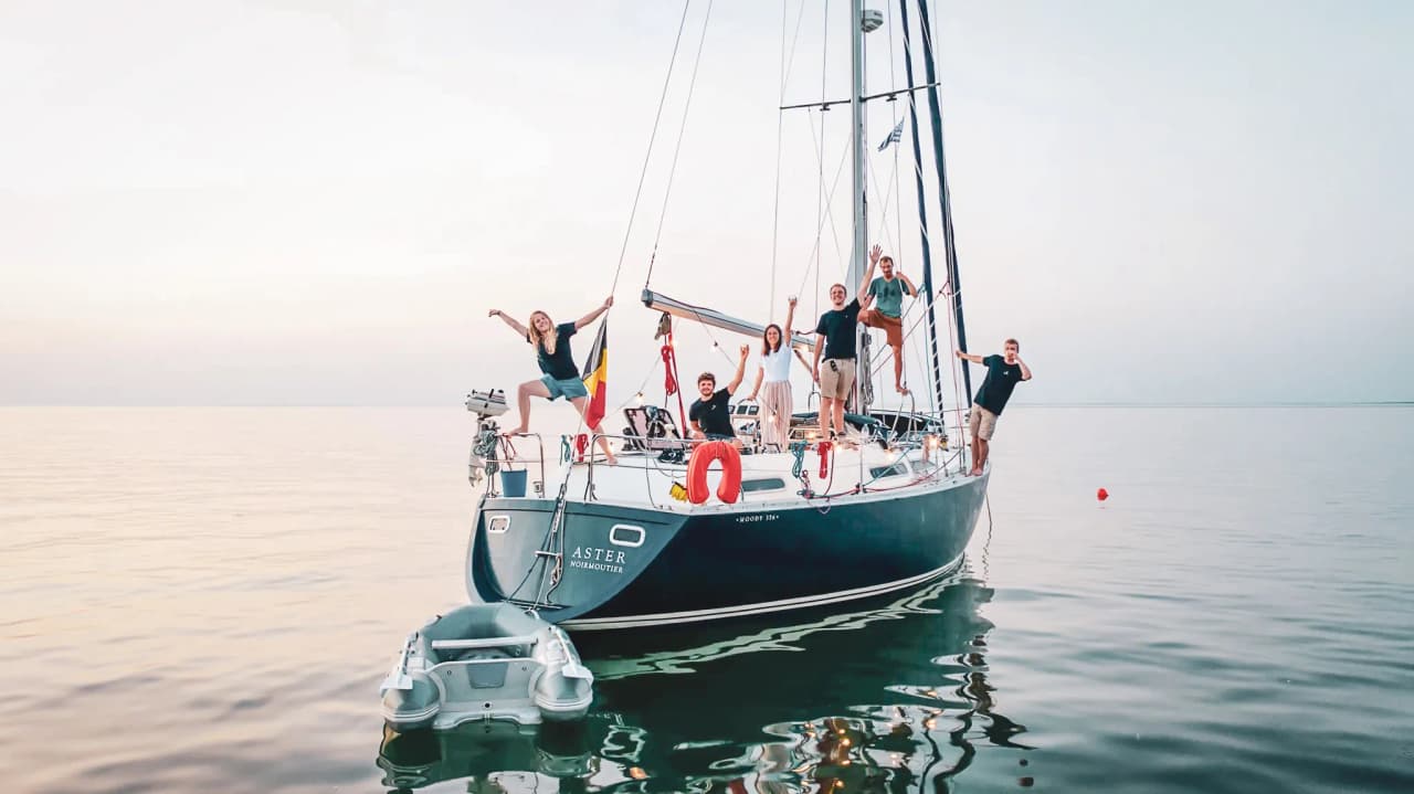 A happy team on a sailing boat at sunset, ready for a maritime adventure.