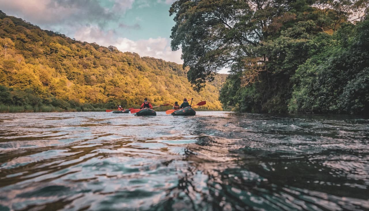 Adventurers in packraft cruising peacefully on a river surrounded by lush greenery.