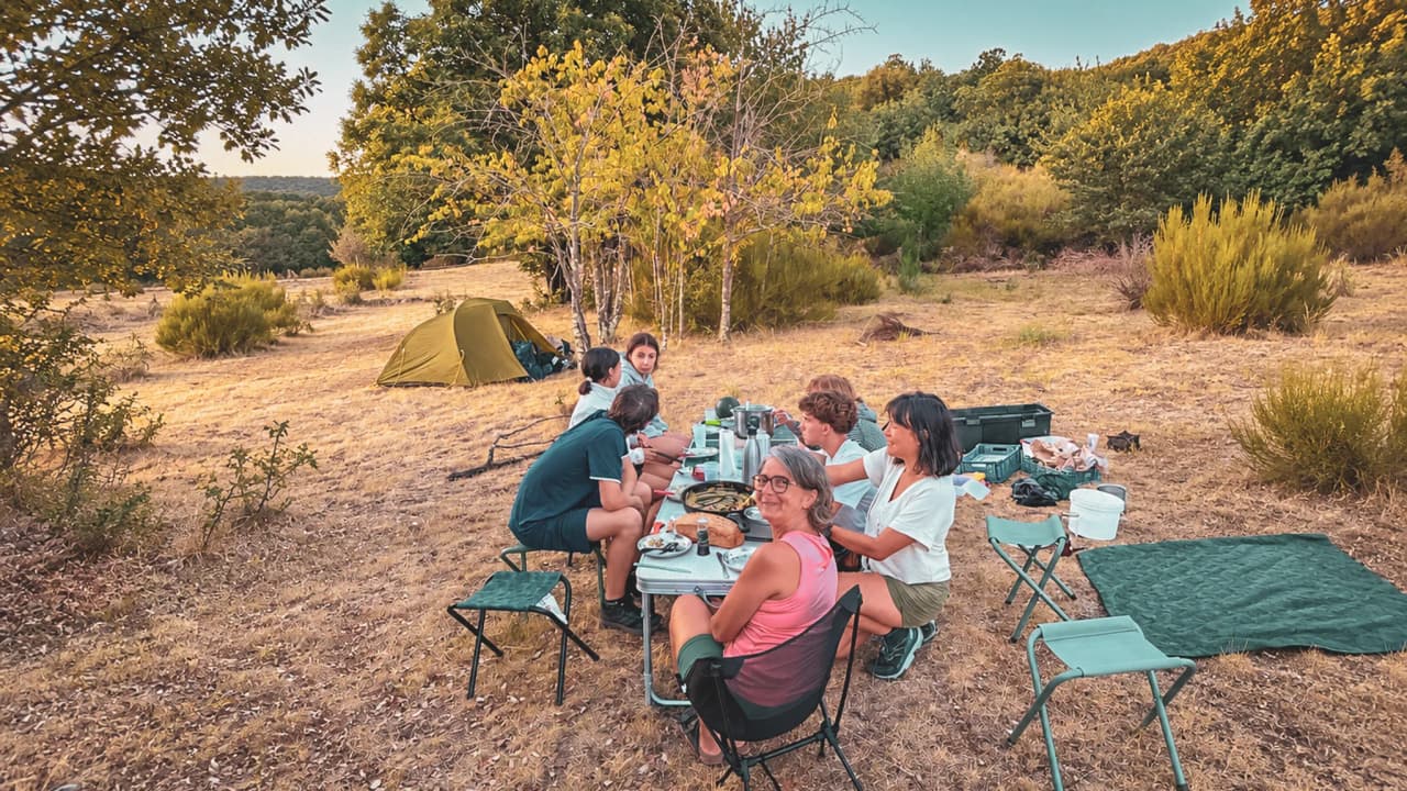 Groupe de randonneurs autour d'une table, sous un ciel étoilé, en pleine nature cévenole.