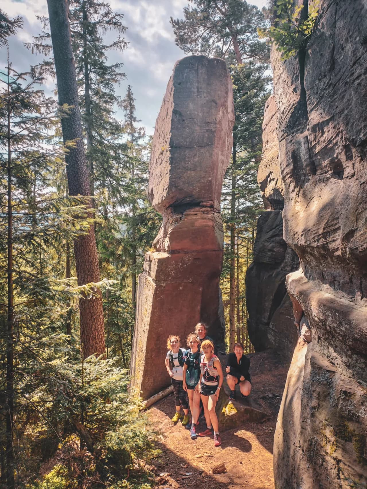 Een groep lachende wandelaars in een bos, omringd door majestueuze rotsen.