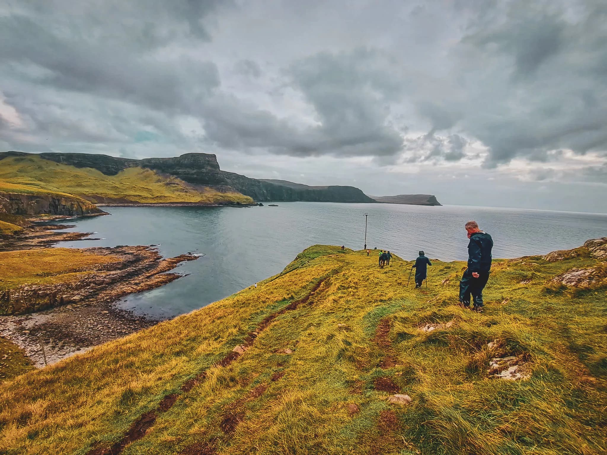 A group of walkers on the rugged coast of the Isle of Skye, with breathtaking scenery in the background.