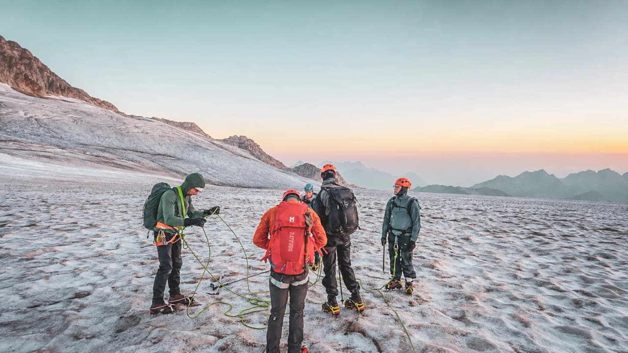 Groupe d'alpinistes sur un glacier au lever du soleil, prêts pour une aventure estivale à Chamonix.