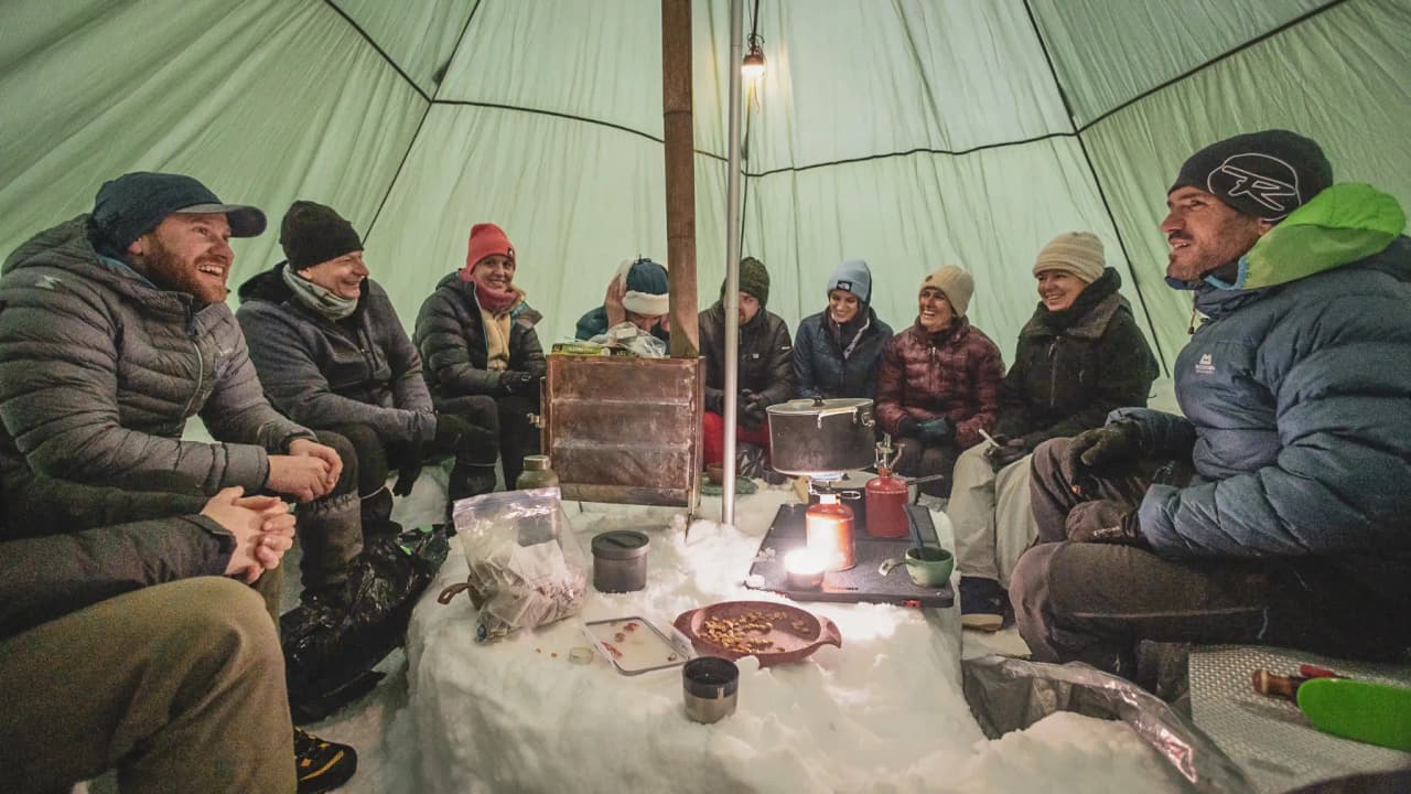 Een gezellige groep die samen een maaltijd geniet in een met sneeuw bedekte Berghut, in een gezellige, bergachtige sfeer.