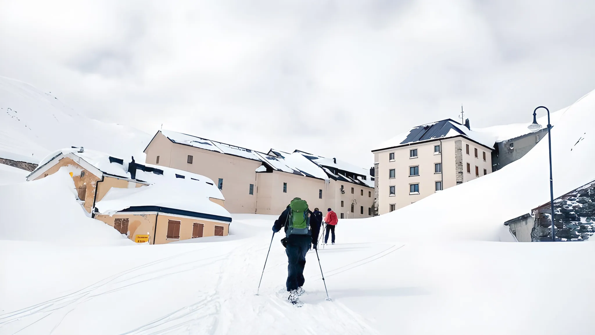 Winterreis: silhouet van een wandelaar op sneeuwschoenen voor besneeuwde gebouwen.