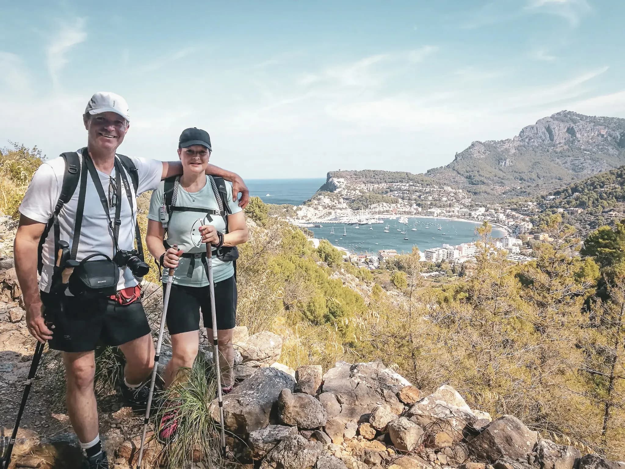 Couple on a hike with panoramic views of the Mallorca coast, surrounded by lush greenery.