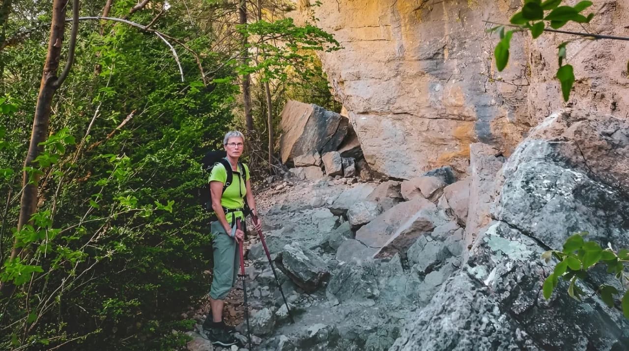 Randonneuse sur un sentier rocheux, entourée par la verdure des Hauts Plateaux du Vercors.