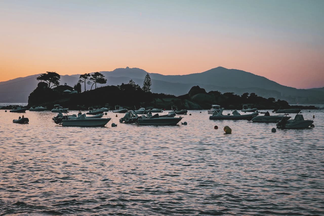 Coucher de soleil sur une mer paisible, des bateaux ancrés, un décor enchanteur en Corse.