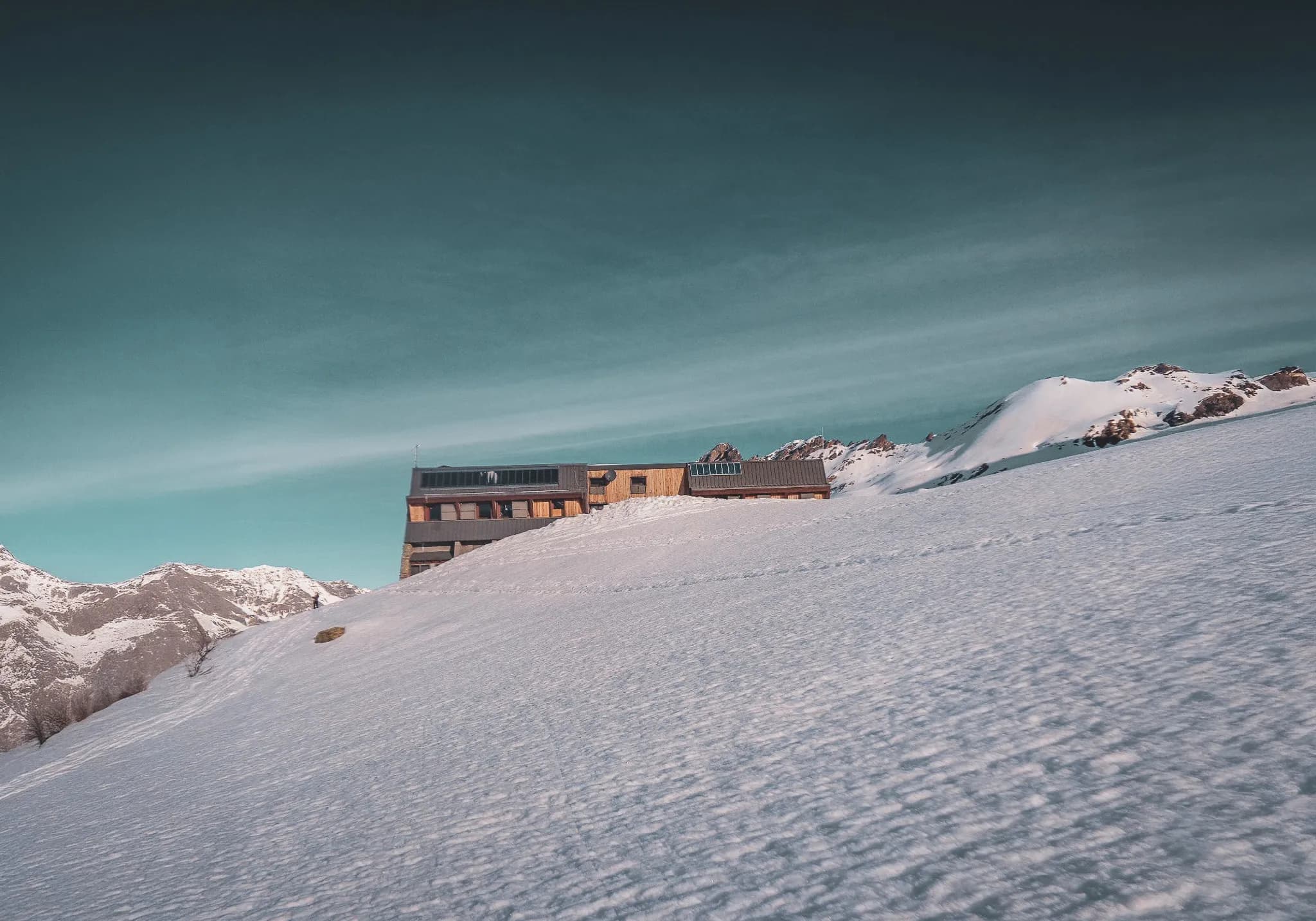 Refuge moderne entouré de neige avec le Mont Viso en toile de fond, invitation à l'aventure.