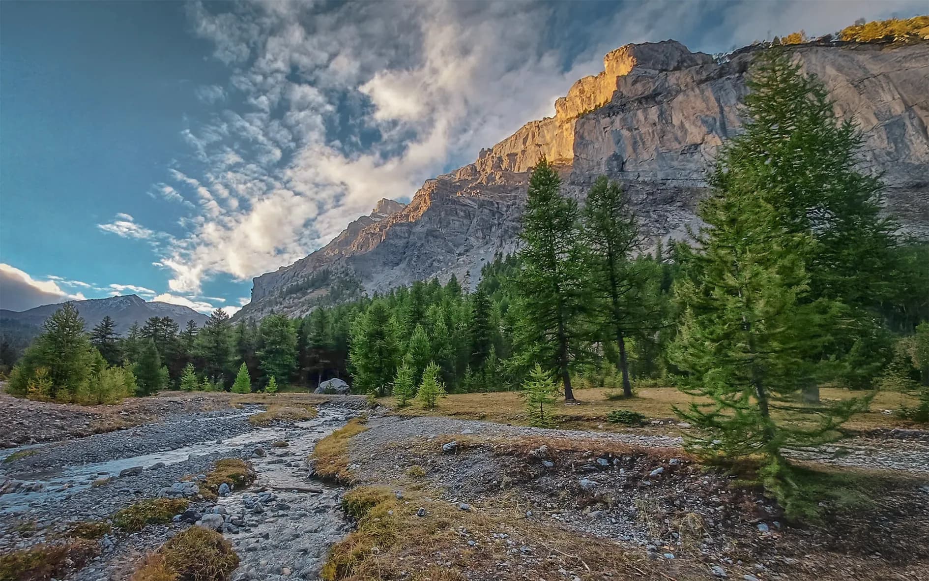 Majestic mountains and a peaceful stream, an invitation to adventure in the heart of nature.